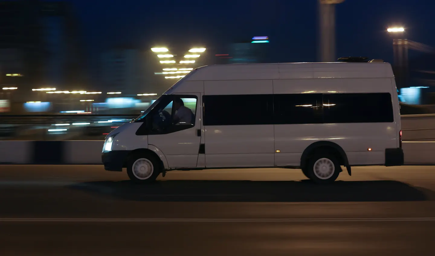 An unbranded white passenger transport van travelling at night